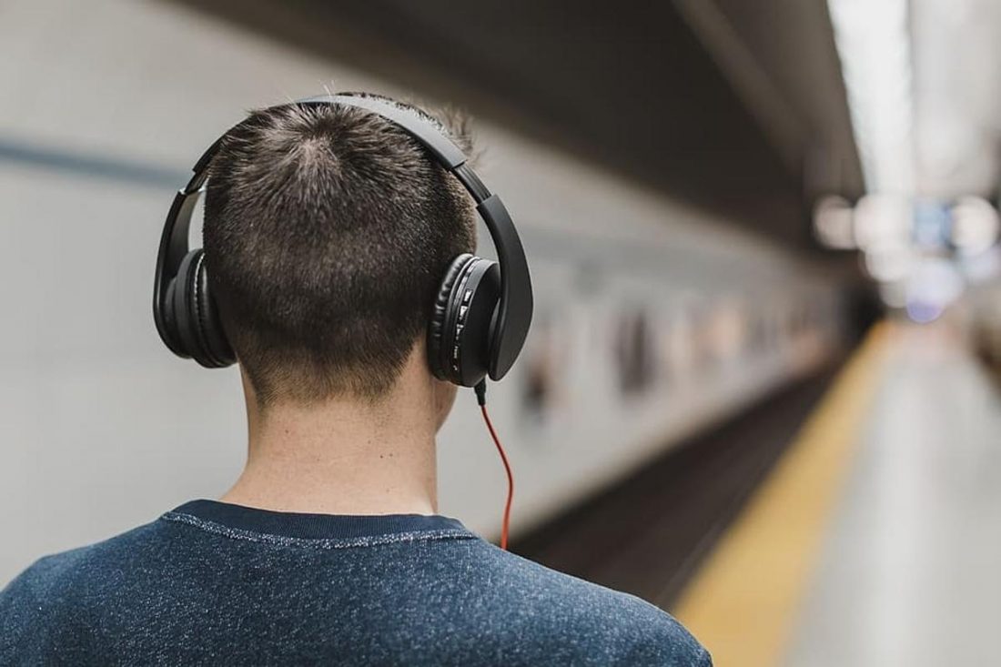 Man walking in train station with headphones on (From: pxfuel.com)