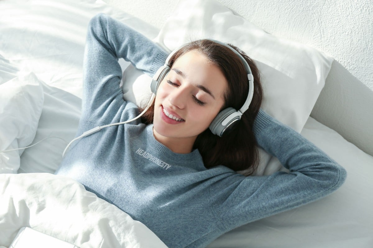 woman sleeping on bed with headphones