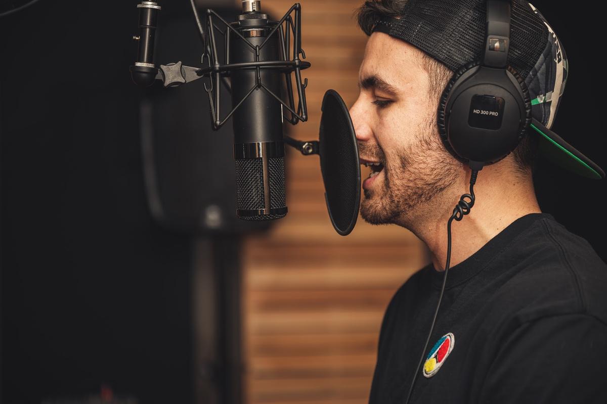 Singer wearing headphones during recording session (From: pexels.com)
