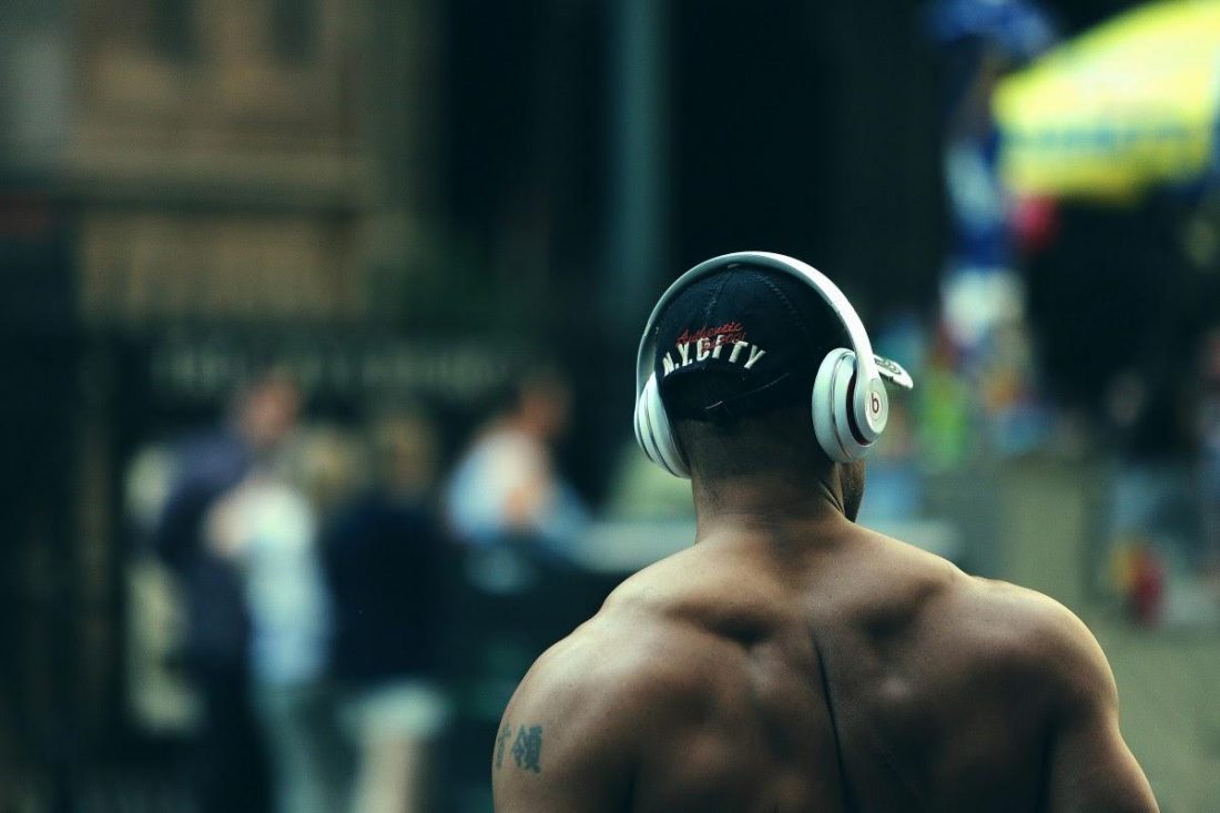 Fit man wearing cap and wireless headphones while working out (From: Pxhere.com)