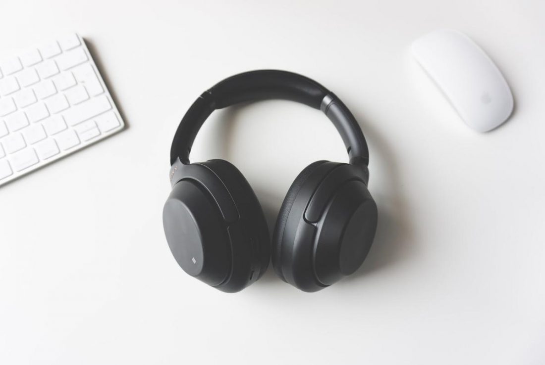 A pair of black noise-cancelling headphones on a desk. (From: Unsplash)