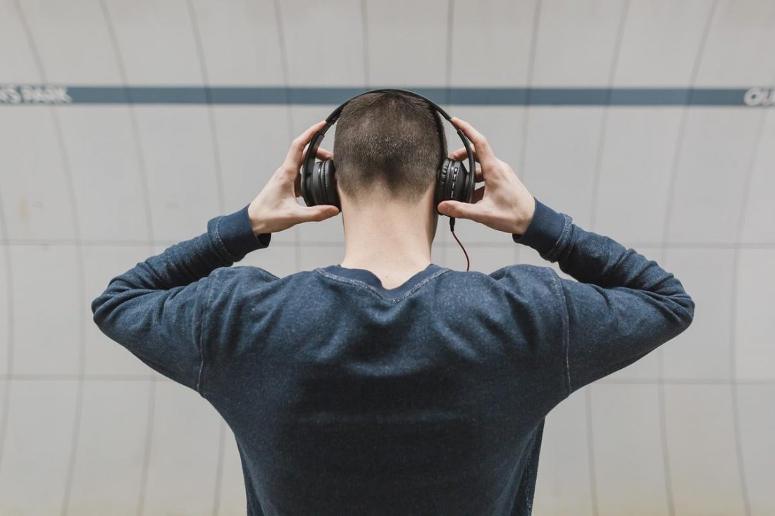 A man adjusting his headphones. (From: Pexels)