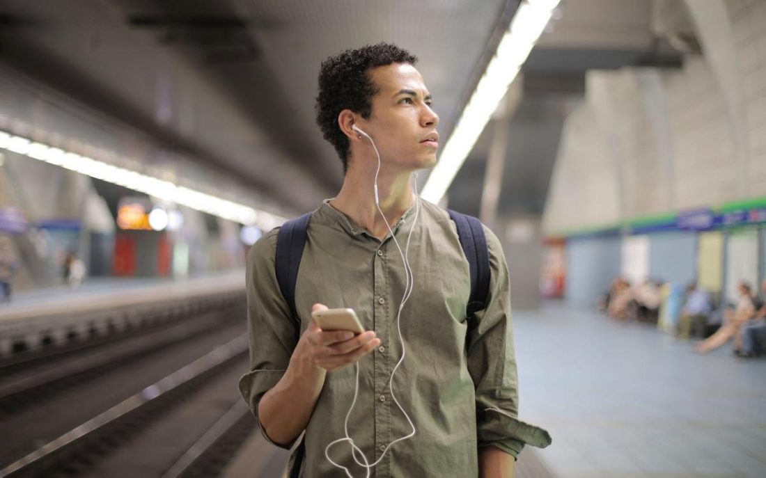 Man wearing earbuds while on subway (From: Pexels)