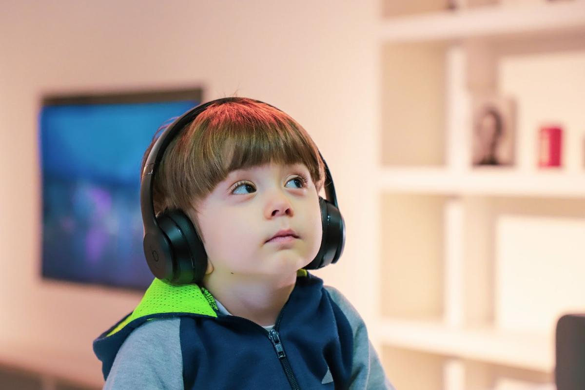 Seorang anak laki-laki memakai headphone.  (Dari: Hapus percikan)