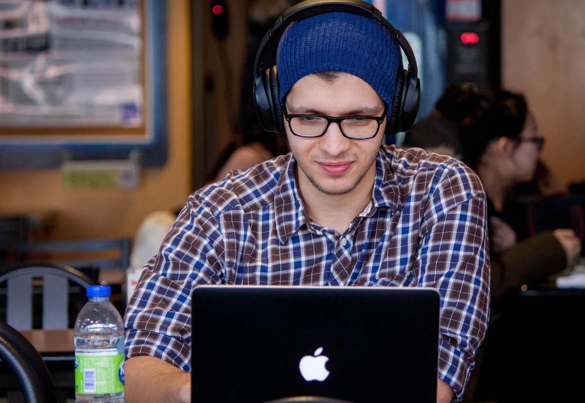 A man wears a beanie underneath his headphones. (From: Unsplash)