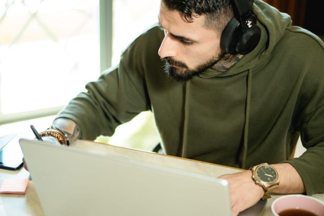 Man wearing headphones while working. (From: Pexels)