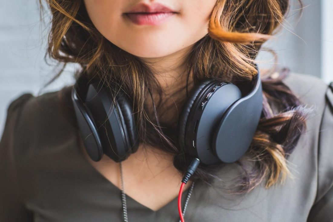 Woman wearing headphones around her neck. (From: Pexels)