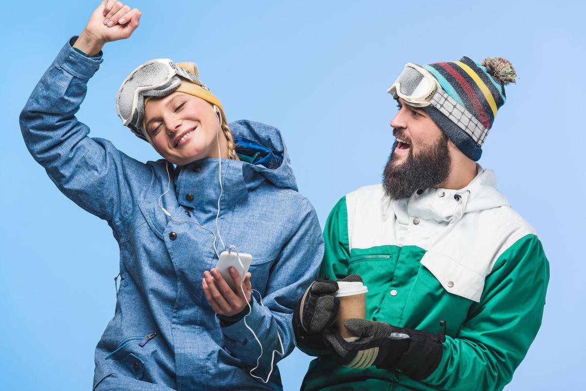 Man and woman in snowboarding gear listening to music (From: Depositphotos)