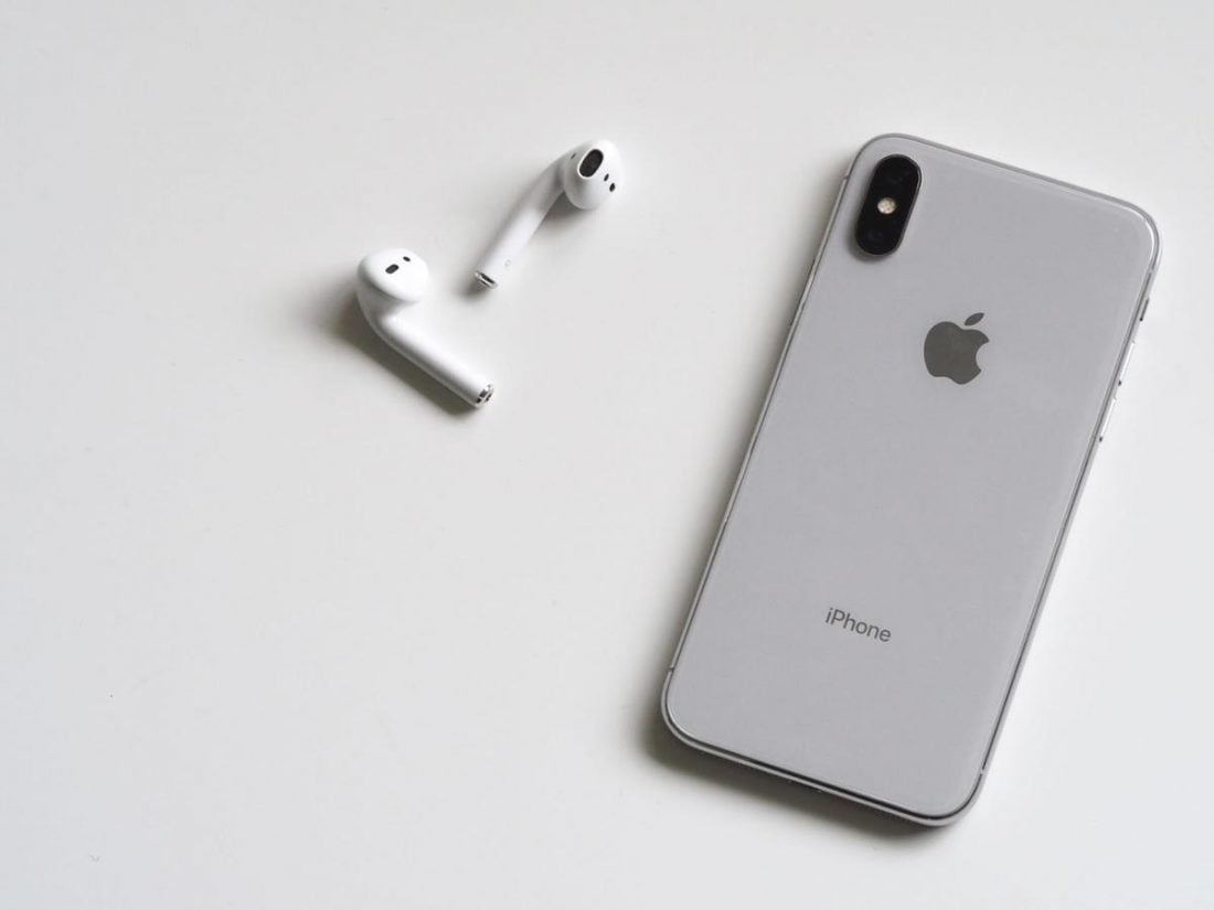An iPhone and a pair of AirPods on a desk. (From: Pexels)