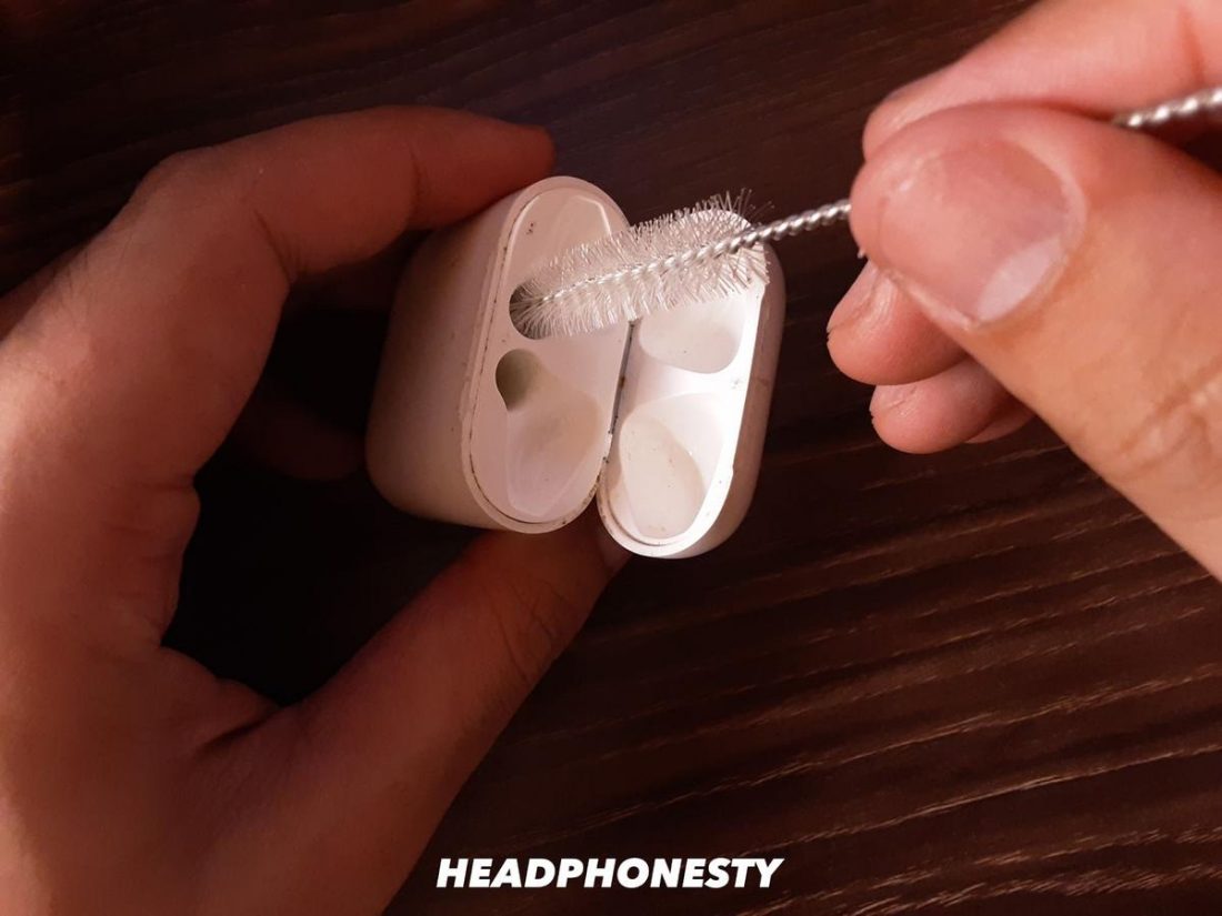 Using a straw brush to clean AirPods case