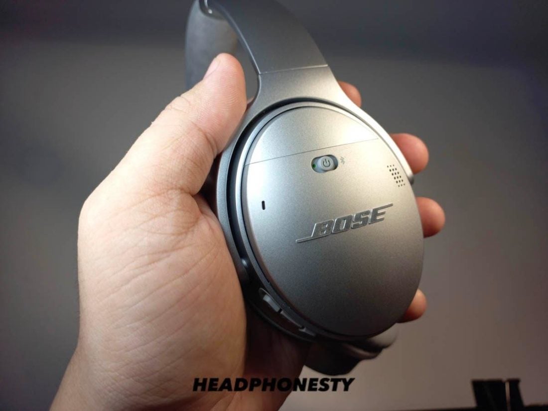 Holding one earcup of Bose headphones