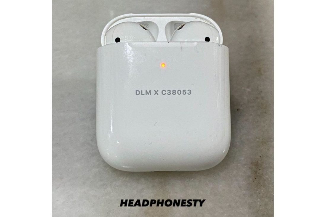 AirPods in their charging case with lid opened flashing amber light.
