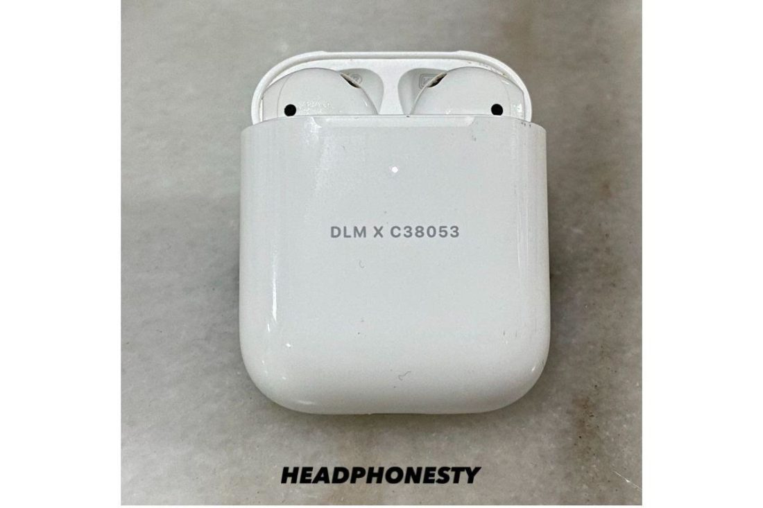 AirPods in their charging case with lid opened flashing white light.