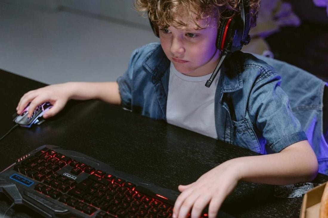Kid wearing headphones while gaming (From: Pexels)