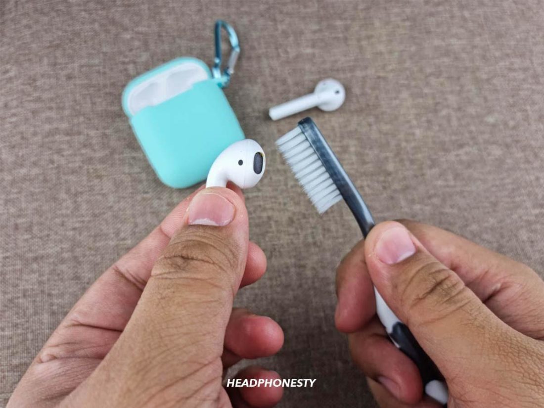 Cleaning AirPods with toothbrush.
