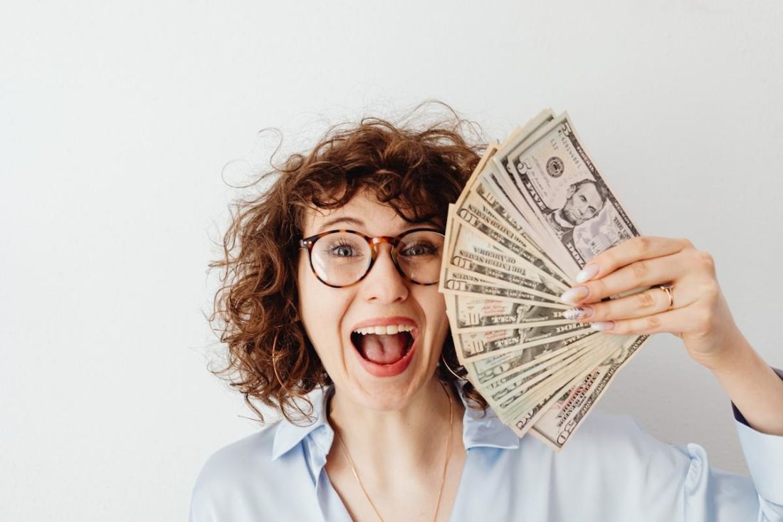 Woman smiling with dollar bills in hand.