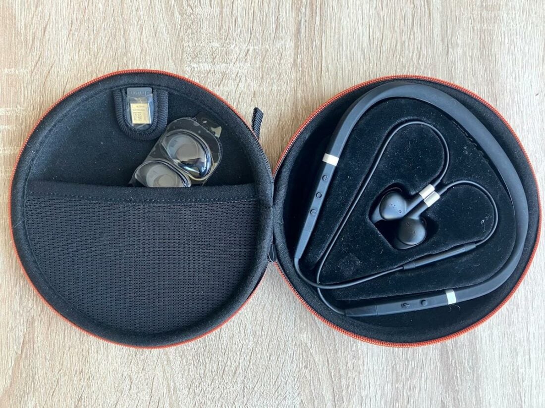 Open case displaying the headset, USB dongle, and earbud accessories.