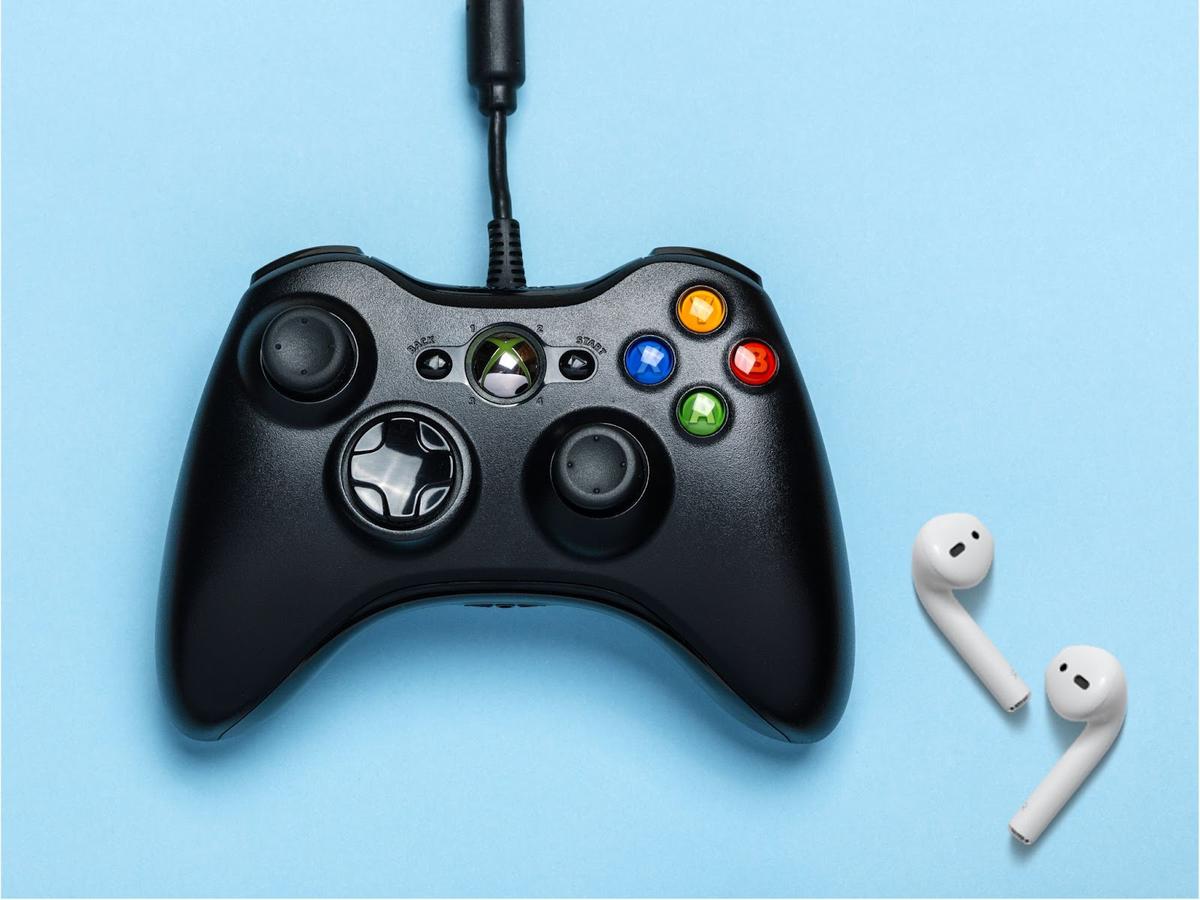 A pair of AirPods beside an Xbox Series X controller.