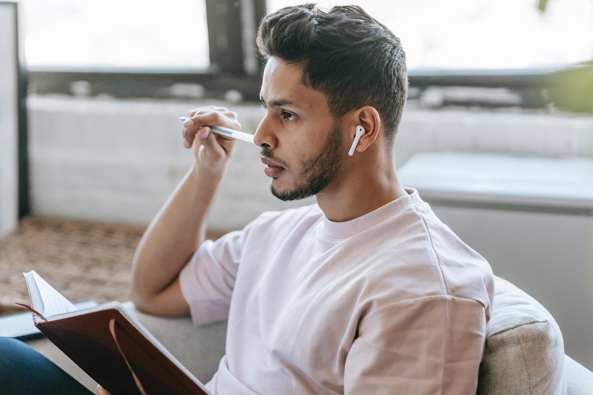 Man wearing earbuds while working from home (From: Pexels).