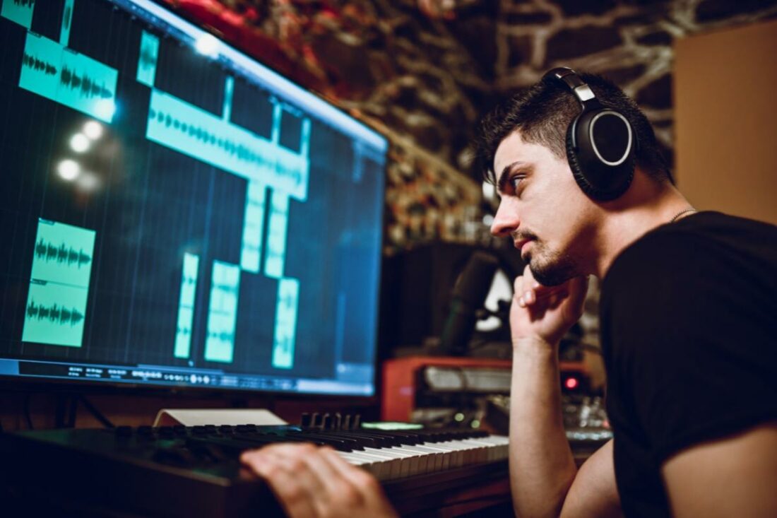 A music producer wearing headphones while mixing a multi-track recording.